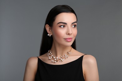Beautiful young woman with elegant jewelry on dark grey background