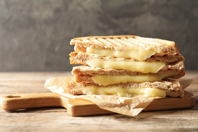 Image of Tasty toast sandwiches with cheese on wooden table