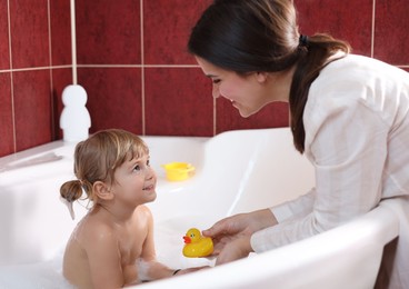 Photo of Happy mother playing with her little daughter in bathroom