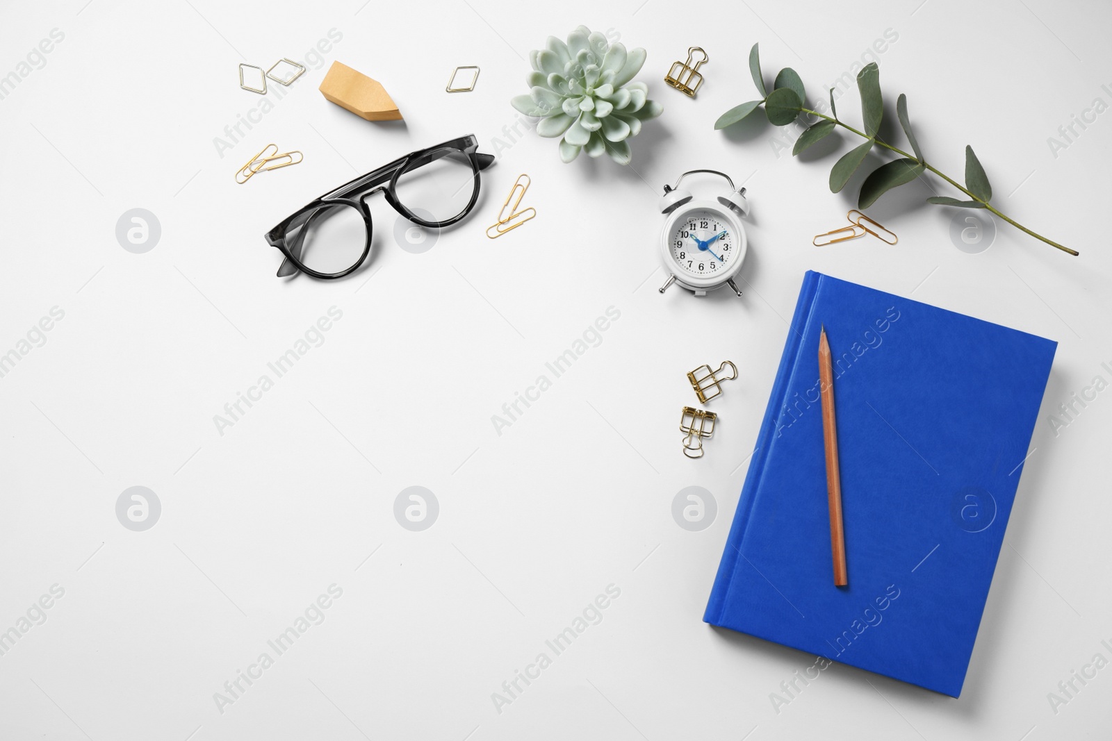 Photo of Glasses, alarm clock, eucalyptus and different stationery on white background, top view. Classic blue - color of the Year 2020