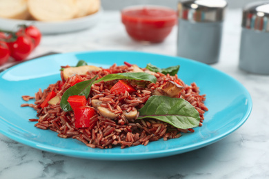 Photo of Tasty brown rice with vegetables on white marble table, closeup