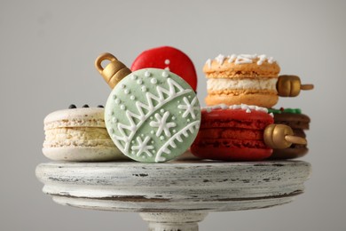 Beautifully decorated Christmas macarons on stand against light grey background, closeup