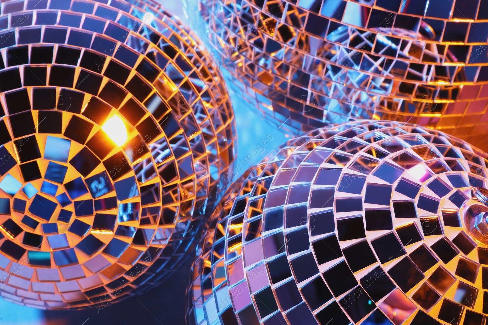 Photo of Bright shiny disco balls on color background, closeup