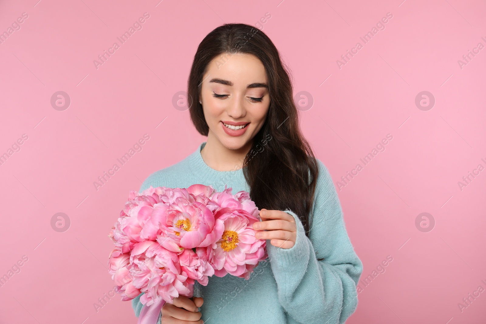 Photo of Beautiful young woman with bouquet of peonies on pink background
