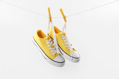 Photo of Stylish sneakers drying on washing line against light grey background