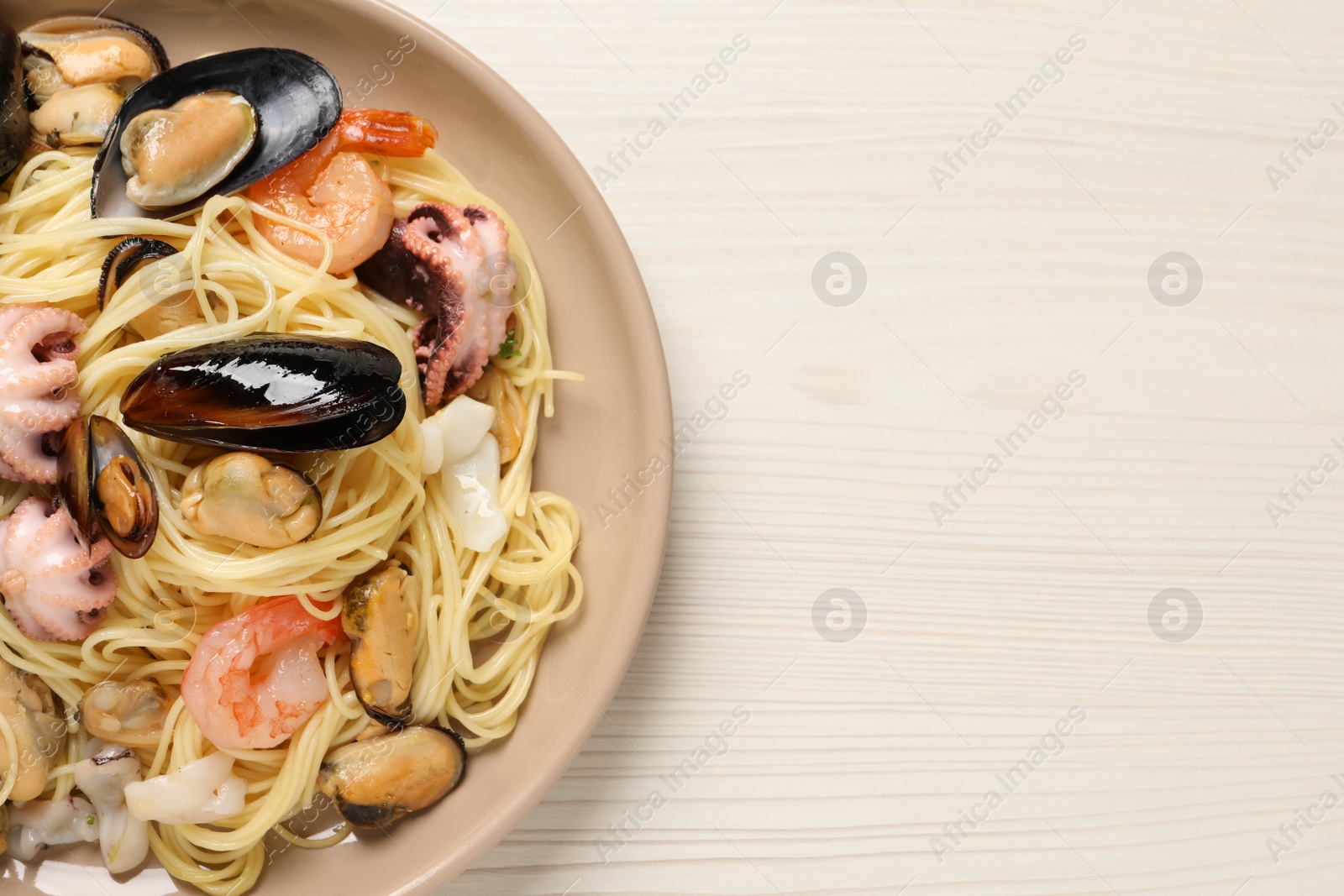 Photo of Delicious pasta with sea food on white wooden table, top view. Space for text