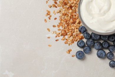 Photo of Bowl of yogurt, granola and blueberries on grey marble table, flat lay. Space for text