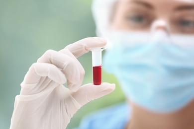 Scientist holding test tube with blood sample in laboratory