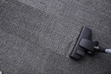 Photo of Modern vacuum cleaner on carpet, top view. Space for text