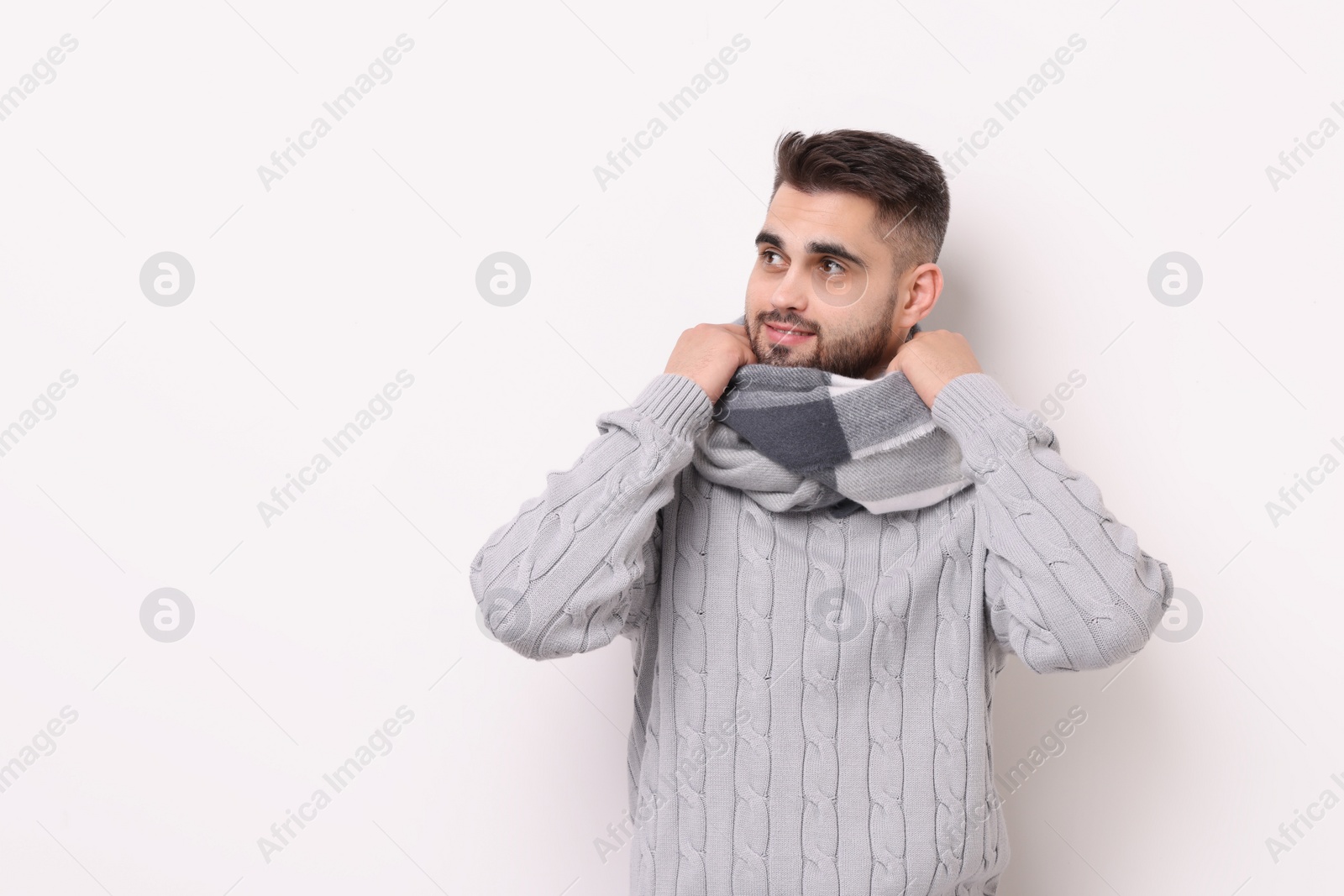 Photo of Portrait of smiling man in warm scarf on light background. Space for text