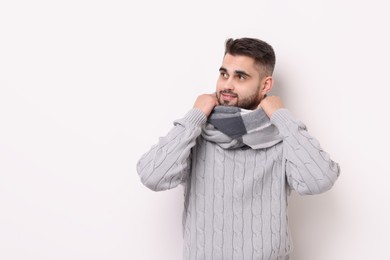 Portrait of smiling man in warm scarf on light background. Space for text