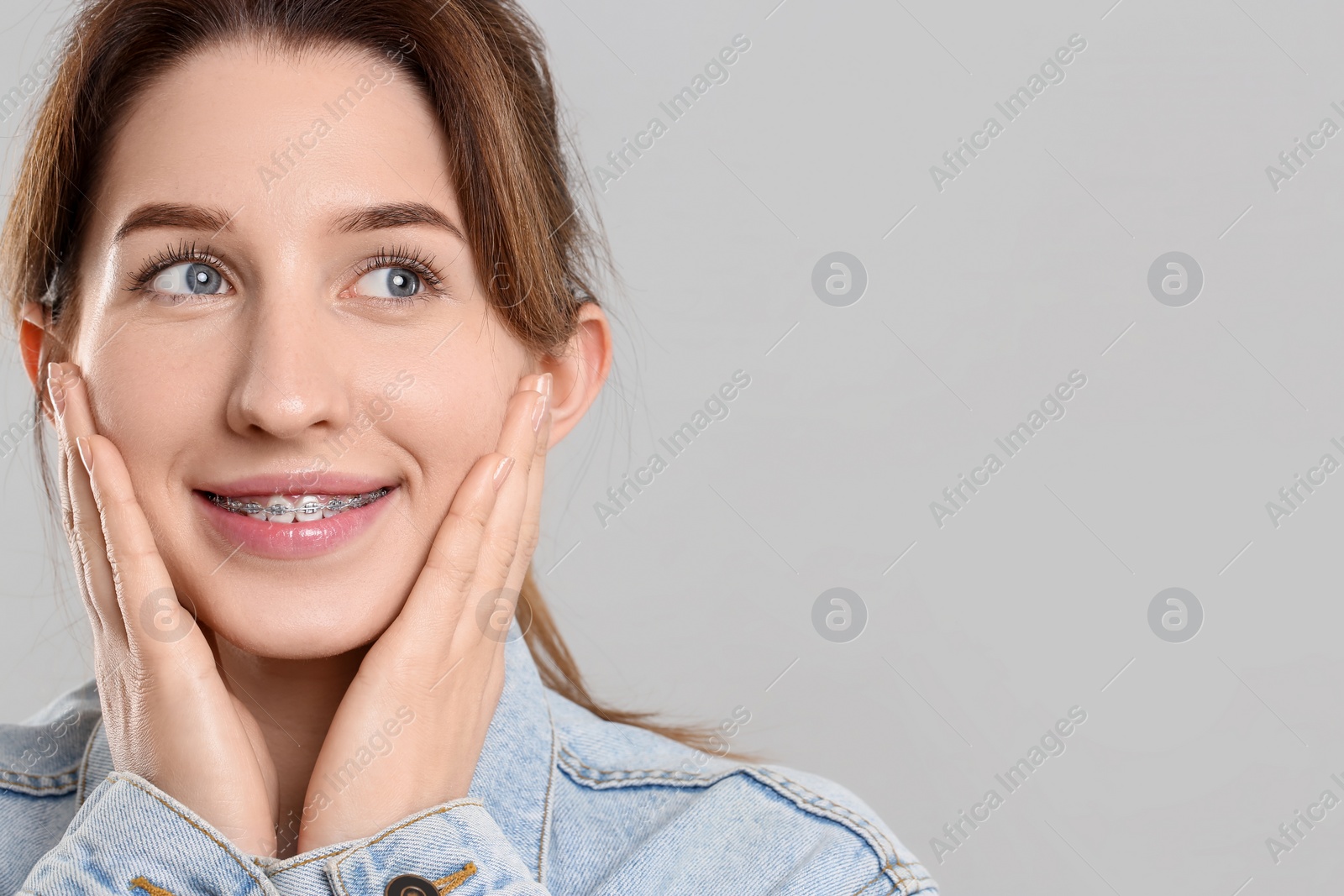 Photo of Portrait of smiling woman with dental braces on grey background. Space for text