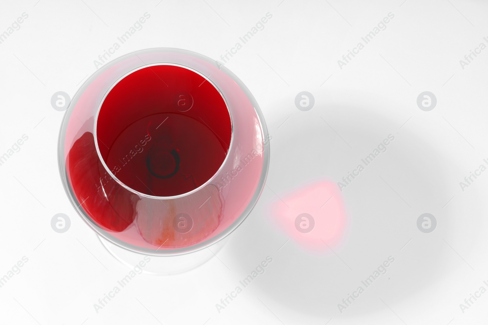 Photo of Red wine in glass and shadow on white background, top view. Space for text