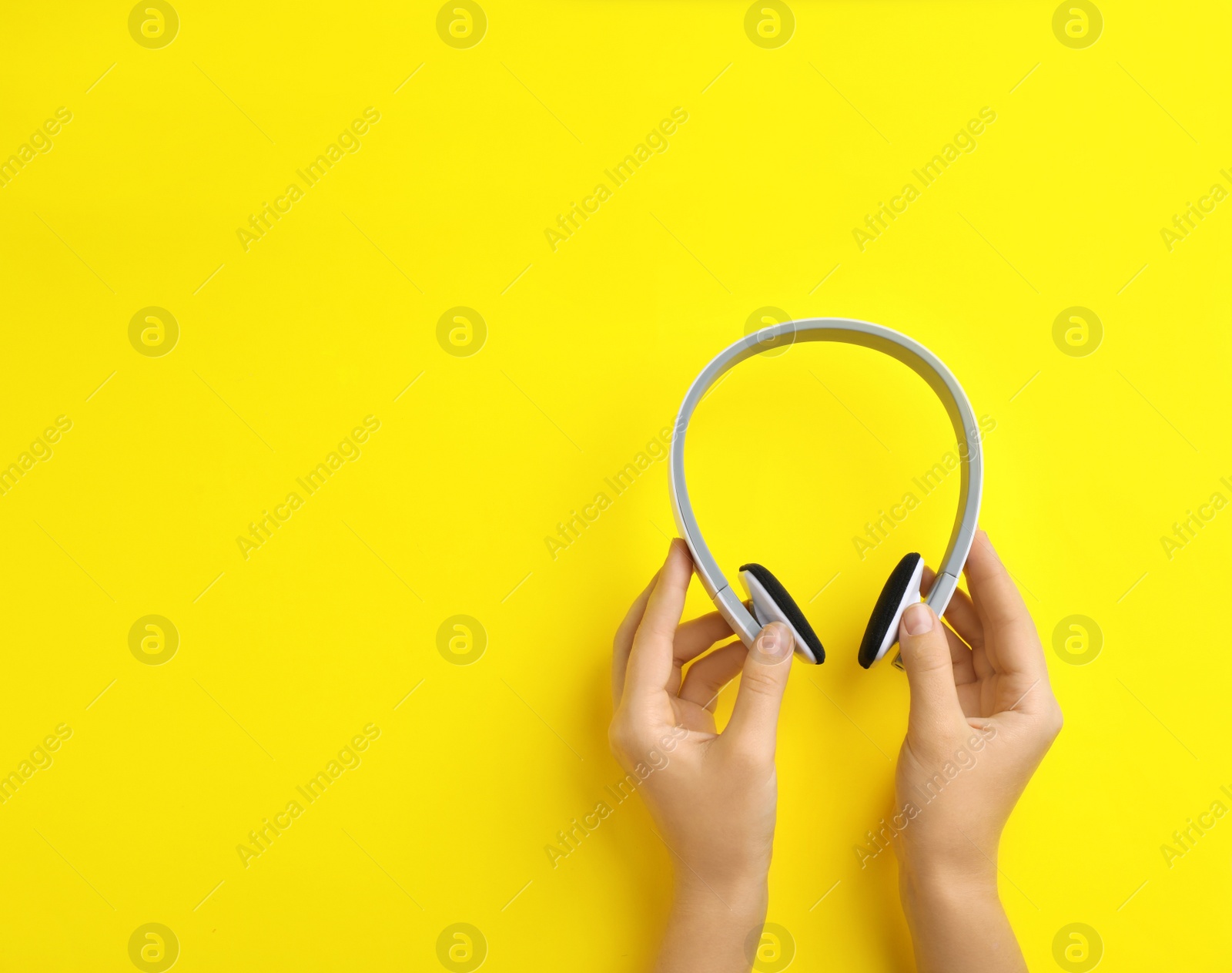 Photo of Woman holding headphones on color background, top view. Space for text