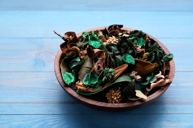 Photo of Aromatic potpourri of dried flowers in bowl on light blue wooden table