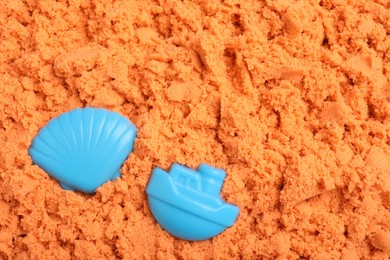 Toys on orange kinetic sand, flat lay