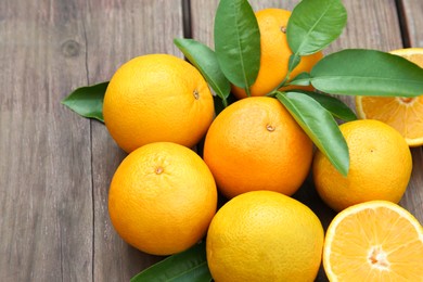 Many ripe oranges and green leaves on wooden table