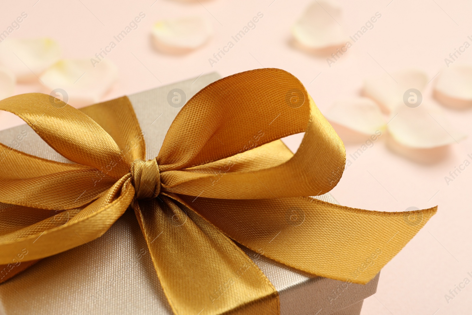 Photo of Beautiful gift box with golden bow on pink background, closeup