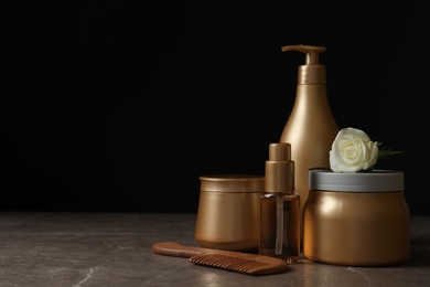 Different hair products, flower and wooden comb on grey table. Space for text