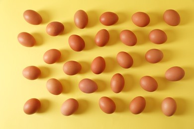 Photo of Fresh chicken eggs on yellow background, flat lay