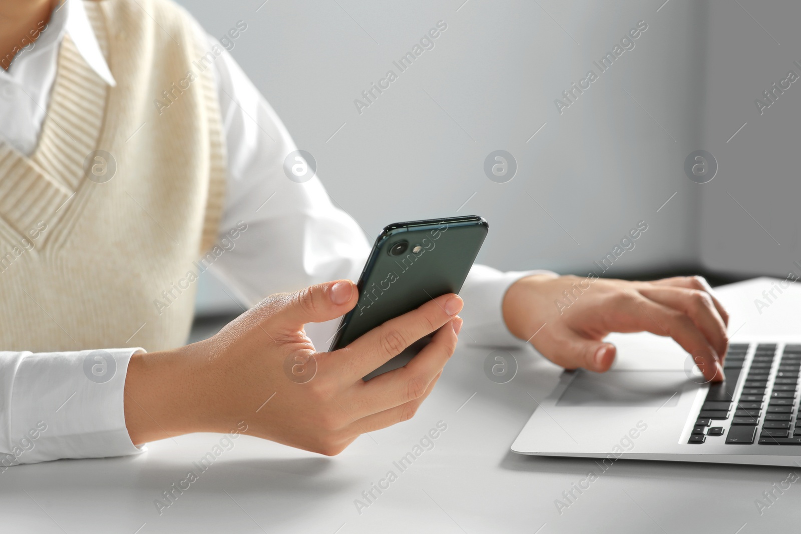 Photo of Woman using smartphone at table indoors, closeup