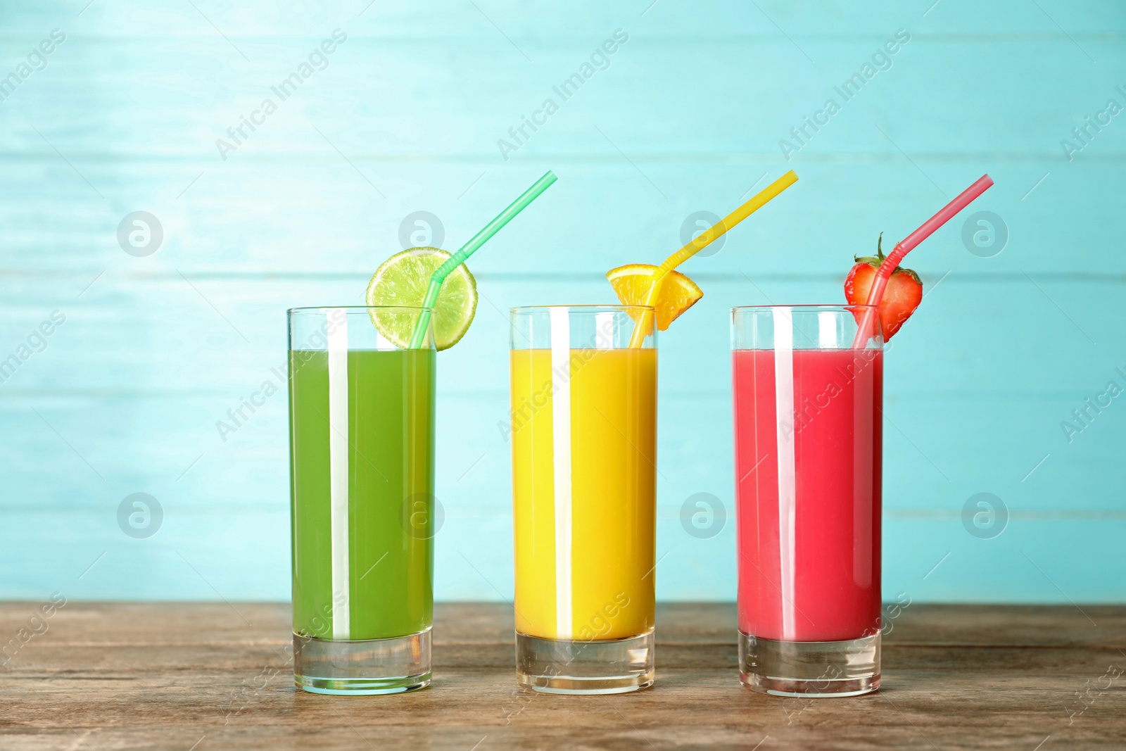 Photo of Three glasses of different juices with straws on table