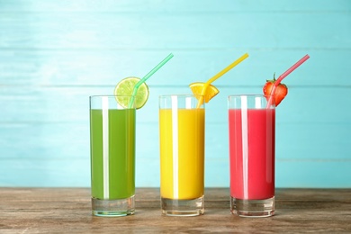 Three glasses of different juices with straws on table