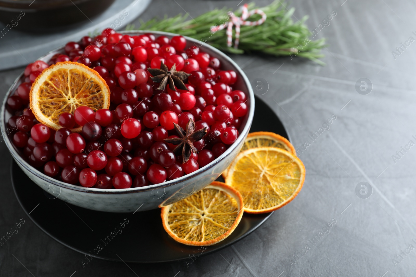 Photo of Fresh ripe cranberries, spices and orange slices on grey table