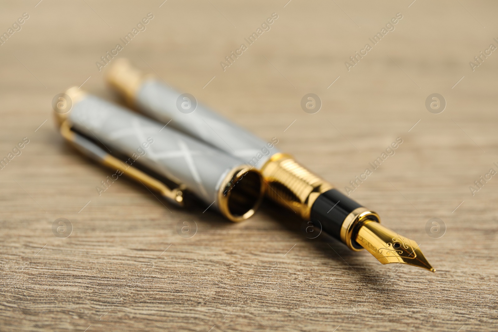 Photo of Beautiful fountain pen with ornate nib on wooden table, closeup