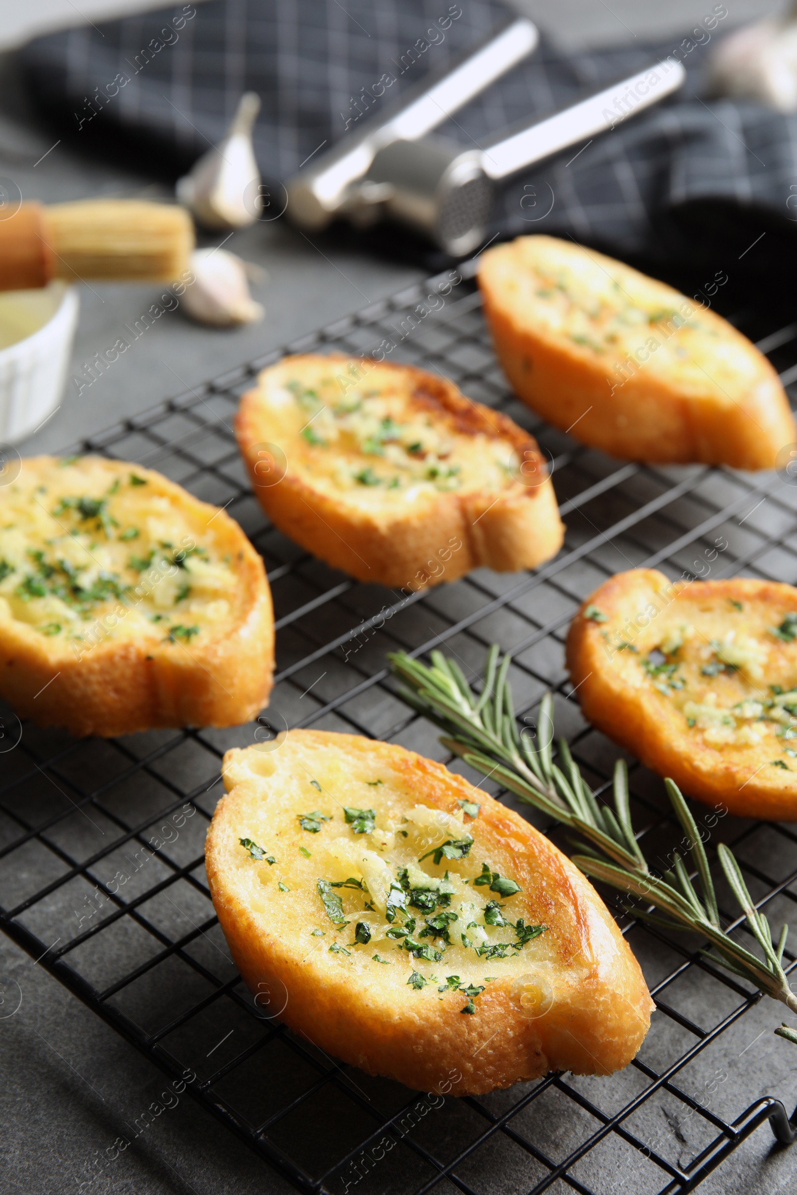 Photo of Baking rack with tasty homemade garlic bread on table