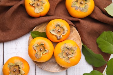 Photo of Delicious ripe juicy persimmons on white wooden table, flat lay