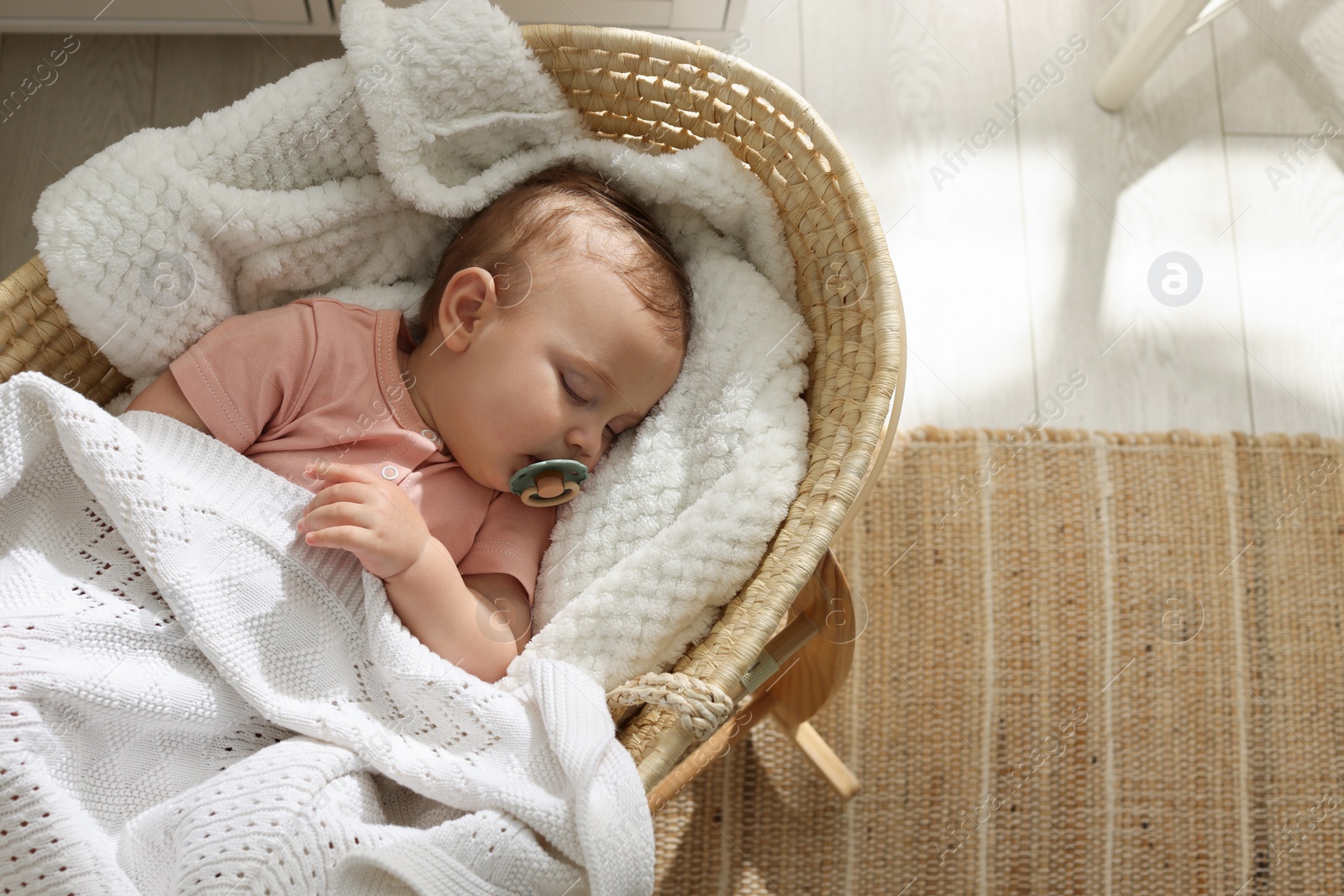 Photo of Cute little baby with pacifier sleeping in wicker crib at home, top view. Space for text