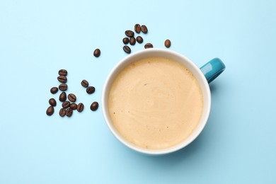 Photo of Fresh coffee in cup and roasted beans on light blue background, top view