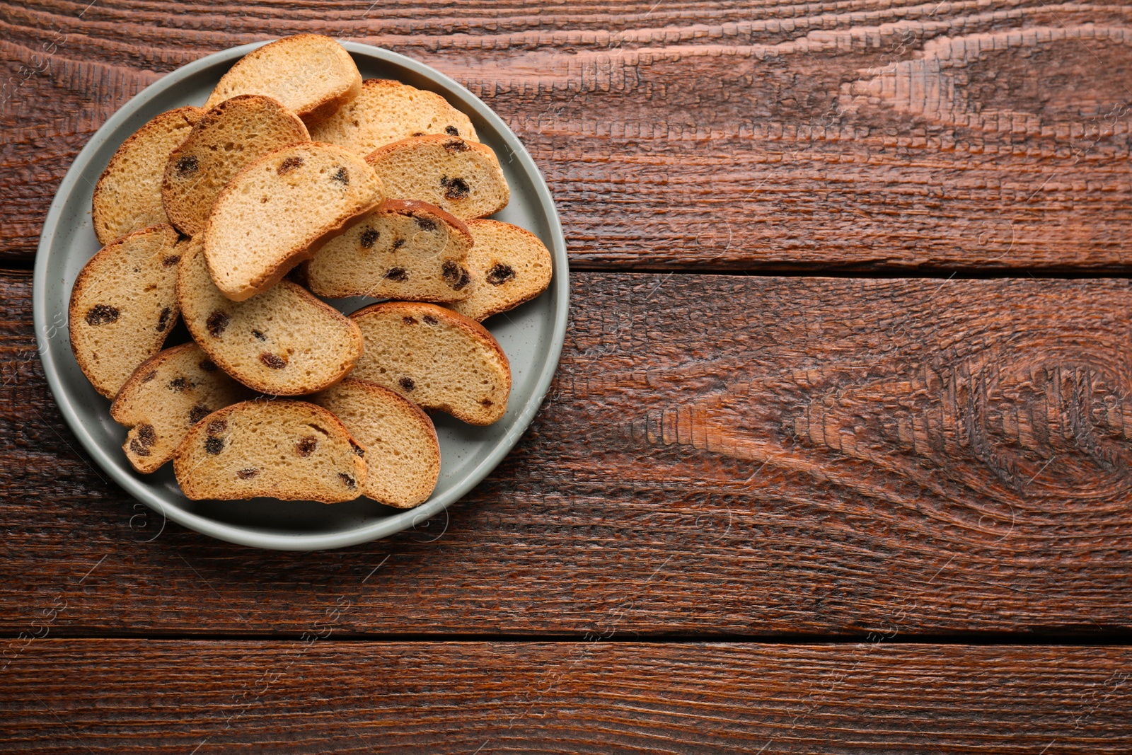 Photo of Plate of sweet hard chuck crackers with raisins on wooden table, top view. Space for text