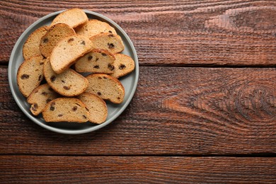 Photo of Plate of sweet hard chuck crackers with raisins on wooden table, top view. Space for text