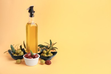 Photo of Bottle of oil, olives and tree twigs on orange background. Space for text