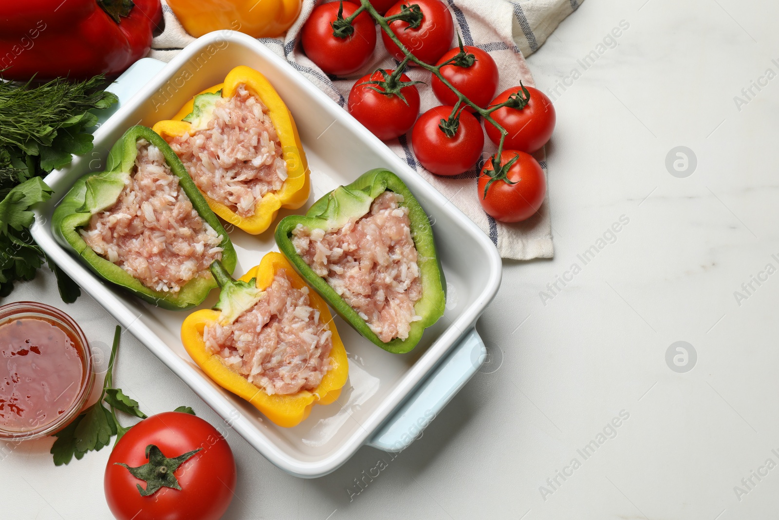 Photo of Raw stuffed peppers and ingredients on white table, flat lay. Space for text