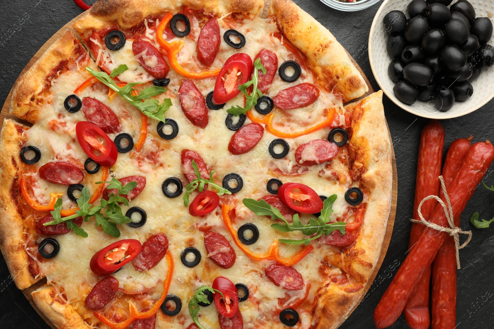 Photo of Tasty pizza and ingredients on black table, top view