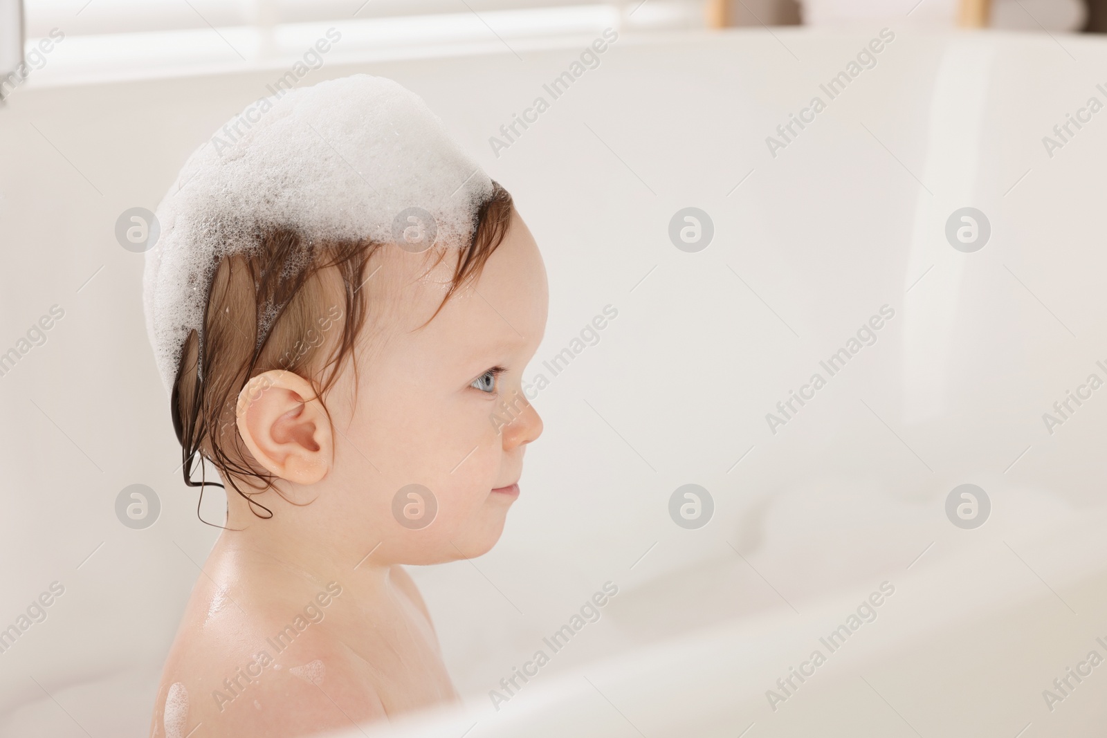 Photo of Cute little baby bathing in tub at home. Space for text