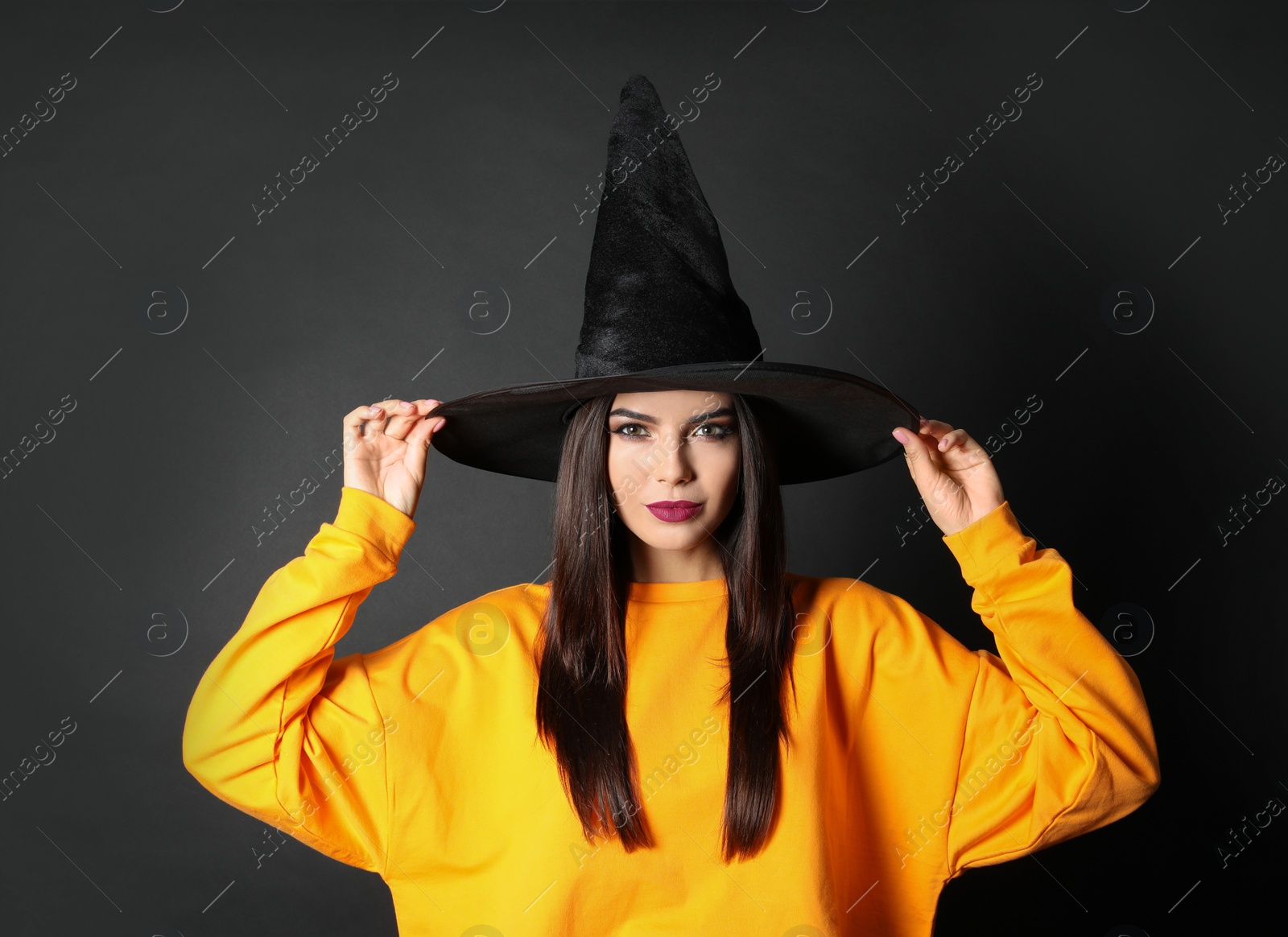 Photo of Beautiful woman wearing witch costume for Halloween party on black background