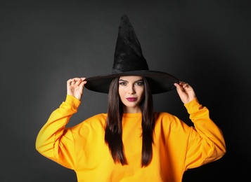 Photo of Beautiful woman wearing witch costume for Halloween party on black background