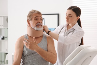 Photo of Orthopedist applying cervical collar onto patient's neck in clinic