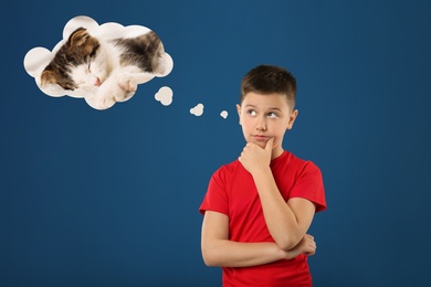 Image of Little boy on blue background dreaming about cute kitten