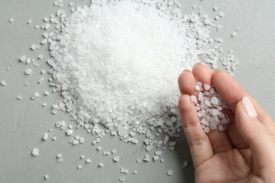 Photo of Woman with natural sea salt at grey table, top view