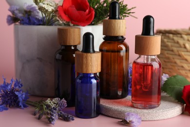 Photo of Aromatherapy. Different essential oils and flowers on pink background