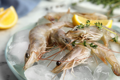 Photo of Raw shrimps with ice and thyme on table, closeup