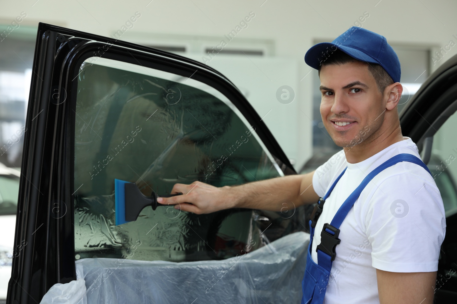 Photo of Worker tinting car window with foil in workshop