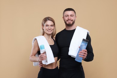 Photo of Athletic people with bottles of water and towels on light brown background