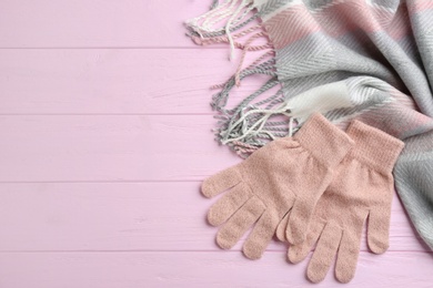 Photo of Stylish gloves and scarf on pink wooden background, flat lay. Space for text