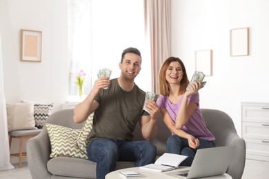 Couple with money on sofa in living room